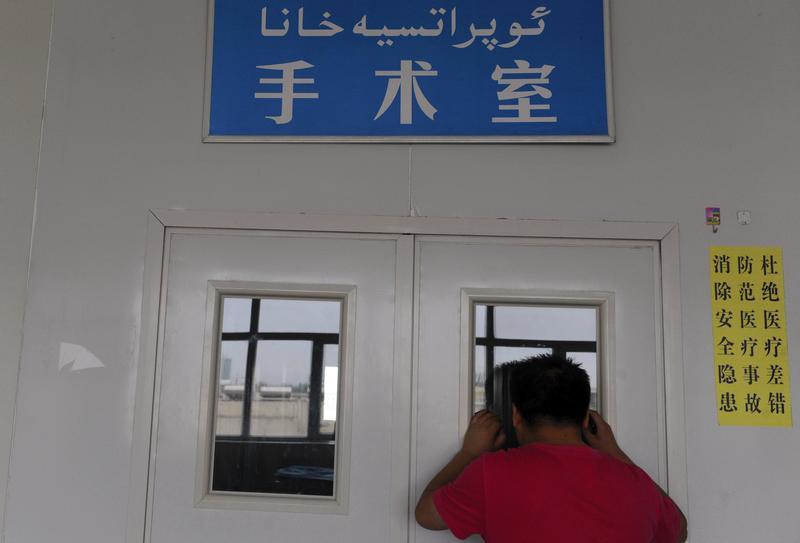 A man looks through a window on the door of an operating room as his wife undergoes a caesarean section at a hospital in Shaya county, Xinjiang Uighur Autonomous Region June 4, 2012. © 2012 Reuters