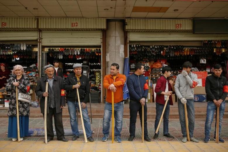 Shopkeepers line up with wooden clubs to perform their daily anti-terror drill outside the bazaar in Kashgar, Xinjiang Uighur Autonomous Region, China, March 24, 2017. REUTERS/Thomas Peter