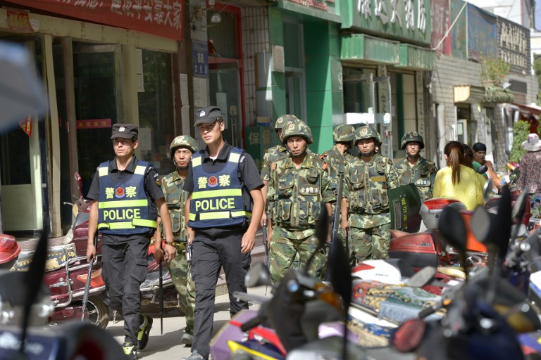 Chinese police officers and paramilitary policemen patrol a street in Kashgar city, July 23, 2014.