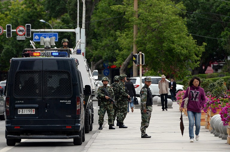 Fully armed Chinese paramilitary police officers stand guard along a street in Urumqi, May 23, 2014.