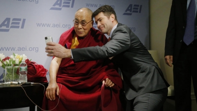 Tibetan spiritual leader the Dalai Lama poses for a "selfie" with blogger and activist Alek Boyd during a break between panel discussions at an event entitled: "Happiness, Free Enterprise, and Human Flourishing" Thursday, Feb. 20, 2014, at the American Enterprise Institute in Washington.