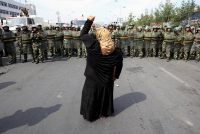 A local woman on a crutch shouts at police during protests in Urumqi in July 2009. As the anniversary of the unrest, which left 200 dead, approaches, China has issued a white paper touting its own tolerance. PHOTO: REUTERS
