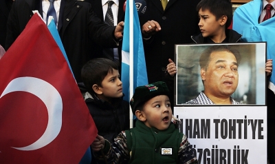An Uygur boy holds a placard with a photo of Ilham Tohti that reads 'Freedom to Ilham Tohti' during a demonstration. Photo: AP