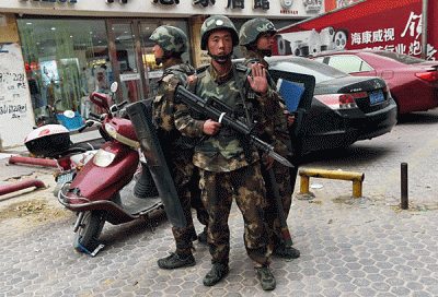 Paramilitary police officers stand guard outside a shopping mall in the town of Hotan, northwestern China's Xinjiang region, April 16, 2015.
