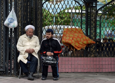An elderly Uyghur talks to a younger man outside a mosque before Friday prayers in Urumqi, capital of western China's Xinjiang region, May 23, 2014.